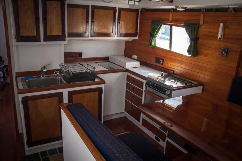 Miss Nina Yacht Photos Pics Interior of 1996 Custom Bolger PH Shoal-draft Ketch with wooden cabinetry and compact kitchen.