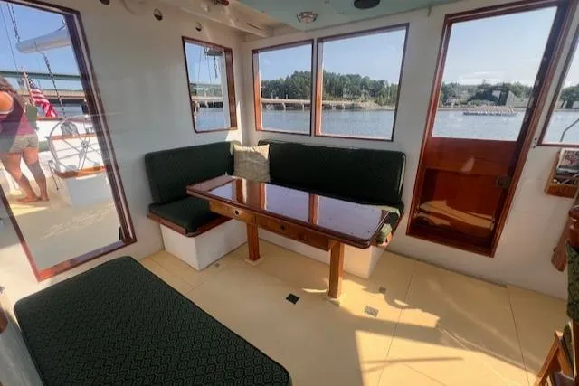 Miss Nina Yacht Photos Pics Interior of 1996 Custom Bolger PH Shoal-draft Ketch with seating and table, overlooking water.