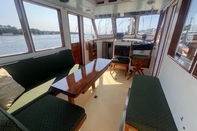 Miss Nina Yacht Photos Pics Interior of 1996 Custom Bolger PH Shoal-draft Ketch with seating and helm, overlooking water.