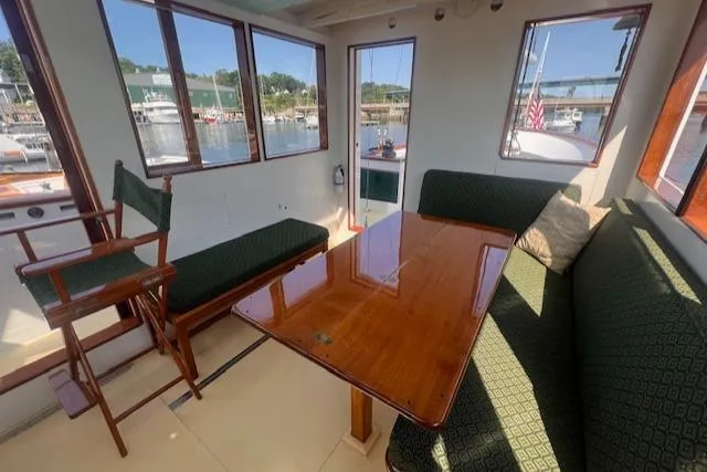 Miss Nina Yacht Photos Pics Interior of 1996 Custom Bolger PH Shoal-draft Ketch with wooden table and green seating.