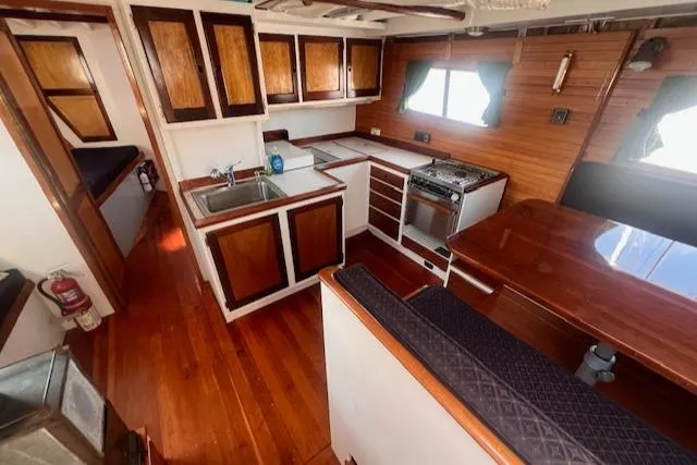 Miss Nina Yacht Photos Pics Interior of 1996 Custom Bolger PH Shoal-draft Ketch with wooden cabinetry and kitchen area.
