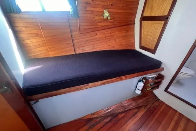 Miss Nina Yacht Photos Pics Cozy cabin interior of 1996 Custom Bolger PH Shoal-draft Ketch with wooden paneling and cushioned bench.