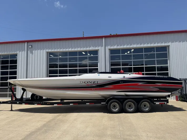  Yacht Photos Pics 2009 Donzi 35ZR speedboat on trailer, parked outside a garage under clear blue sky.