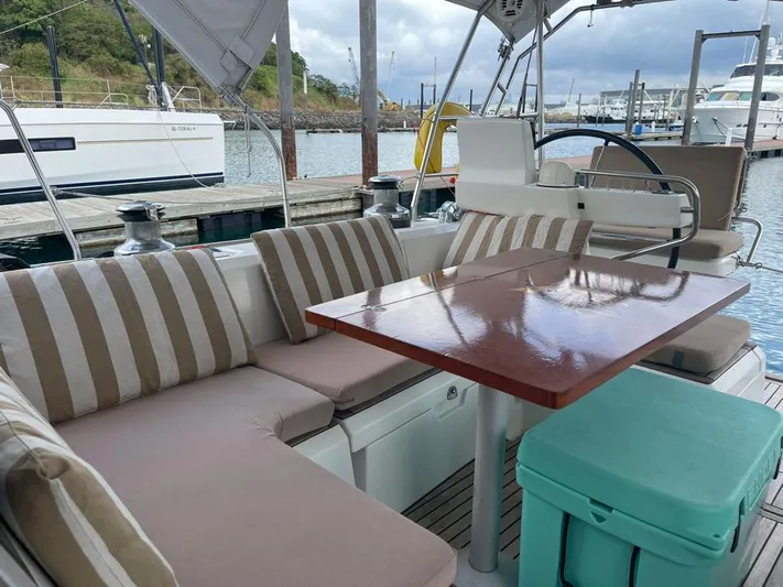 La Vieja Yacht Photos Pics Beneteau Sense 50 yacht cockpit with striped cushions, wooden table, and marina view.