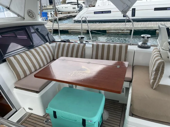 La Vieja Yacht Photos Pics Cozy seating area on a 2011 Beneteau Sense 50 yacht with striped cushions and wooden table.