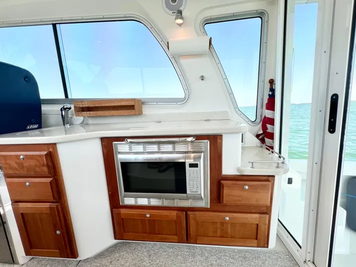 Traveller Yacht Photos Pics Interior of 2016 Back Cove 34 boat with kitchen area, featuring microwave and wooden cabinetry.