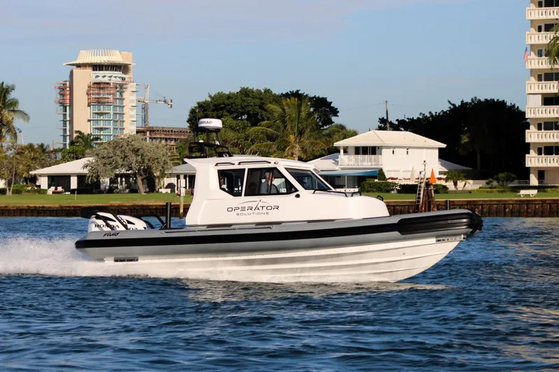 Operator 01 Yacht Photos Pics 2022 Fluid Watercraft Patrol 880 Cabin cruising on a sunny day near waterfront buildings.