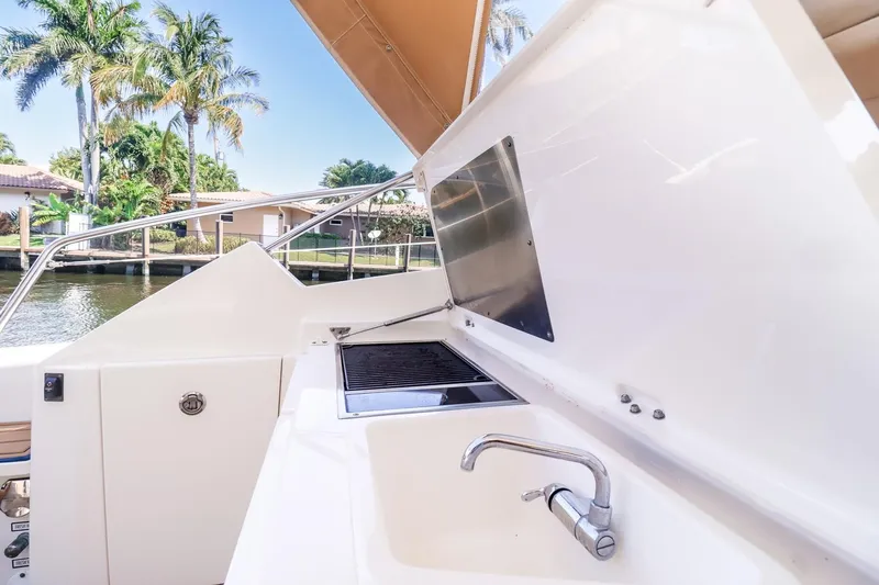 Ocean's Grace Yacht Photos Pics Outdoor kitchen on 2016 Pursuit SC 365i boat with sink and grill, near waterfront.