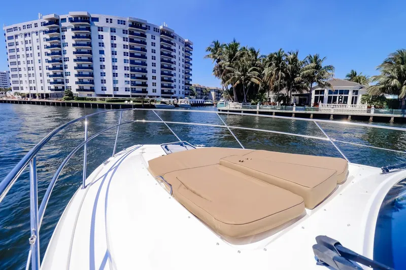 Ocean's Grace Yacht Photos Pics 2016 Pursuit SC 365i boat with sun pads, cruising near waterfront buildings and palm trees.