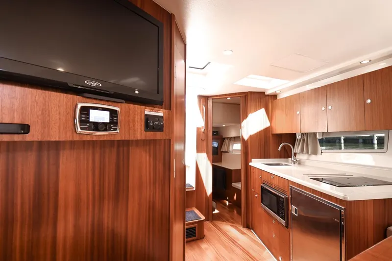 Ocean's Grace Yacht Photos Pics 2016 Pursuit SC 365i yacht interior with modern kitchen, wood cabinetry, and entertainment system.