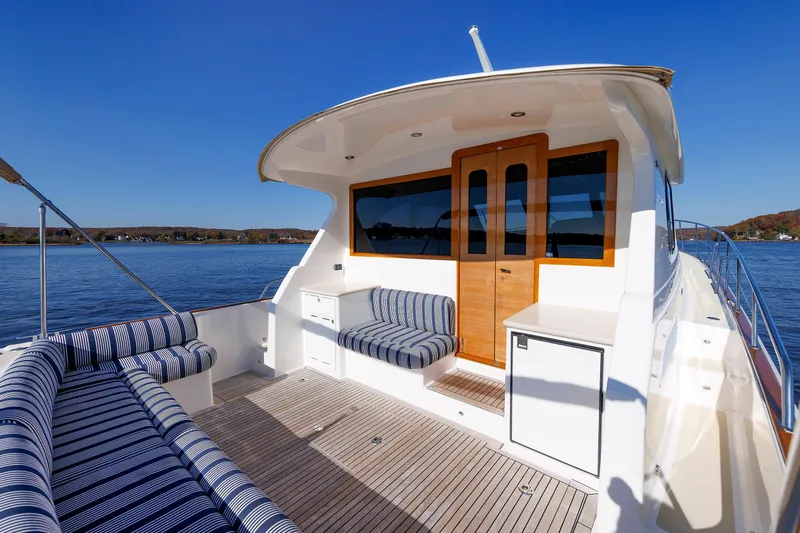 Friendly Persuasion Yacht Photos Pics 2019 Grand Banks 44 Eastbay SX yacht with striped seating, wooden doors, and scenic water view.