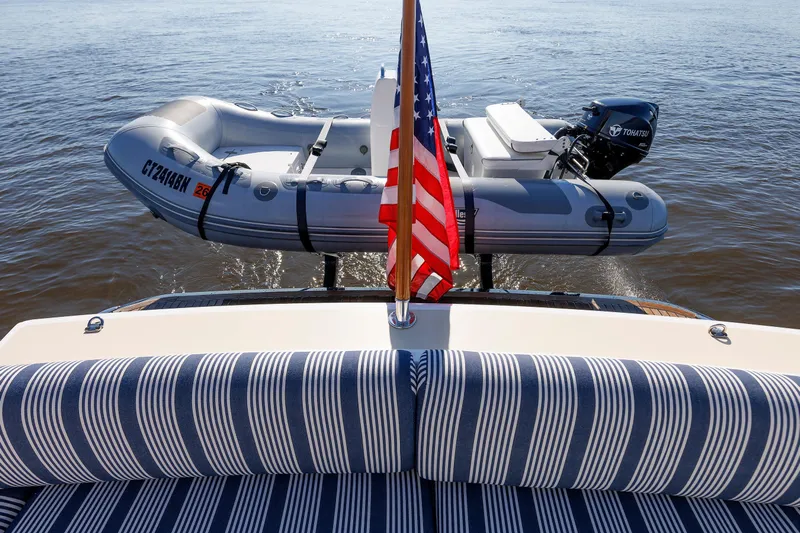 Friendly Persuasion Yacht Photos Pics 2019 Grand Banks 44 Eastbay SX with striped seating, American flag, and inflatable boat on water.