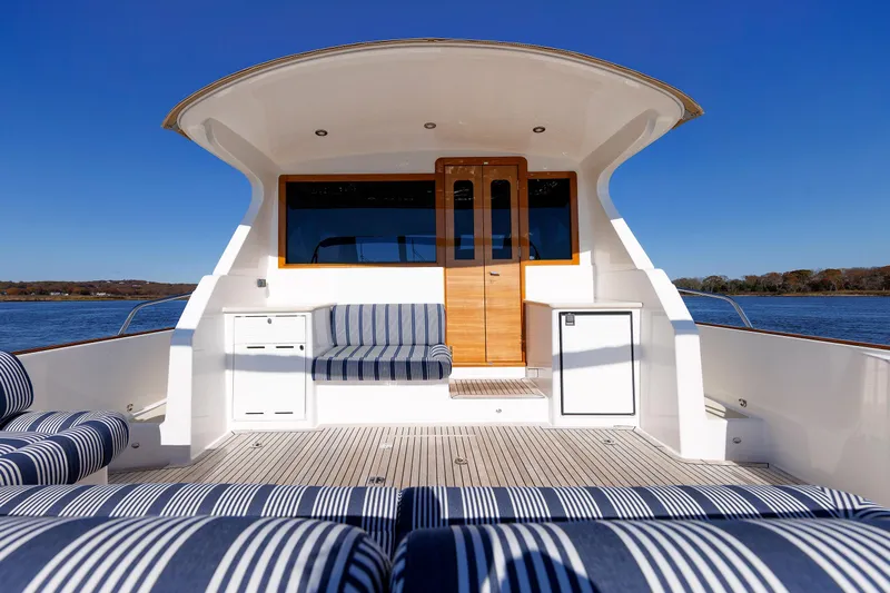 Friendly Persuasion Yacht Photos Pics 2019 Grand Banks 44 Eastbay SX yacht with striped seating, wooden door, and ocean view.