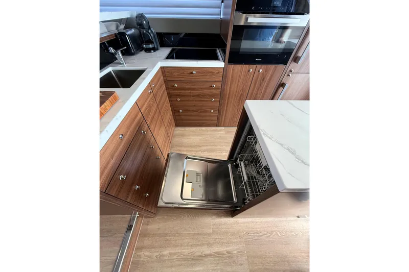  Yacht Photos Pics Modern kitchen in 2023 Maritimo M600 yacht with open dishwasher and sleek wood cabinetry.