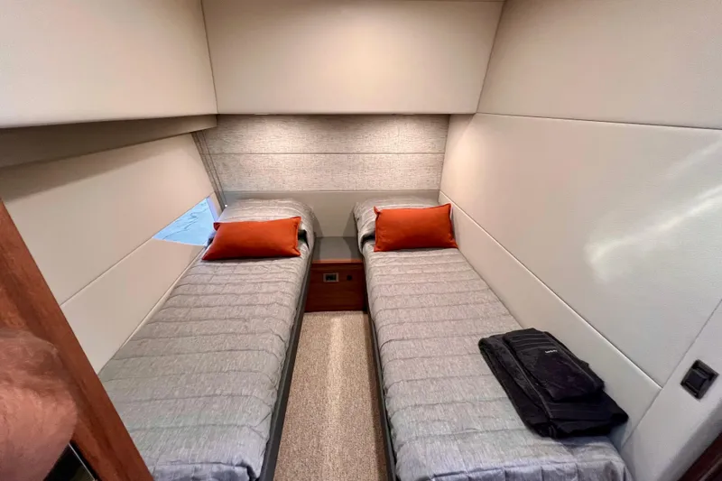  Yacht Photos Pics 2023 Maritimo M600 yacht cabin with twin beds, gray bedding, and orange pillows.