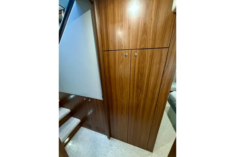  Yacht Photos Pics 2023 Maritimo M600 yacht interior with wooden cabinetry and carpeted stairs.