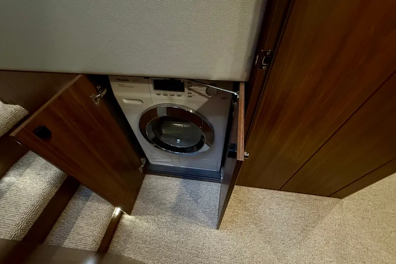  Yacht Photos Pics 2023 Maritimo M600 yacht interior with built-in washing machine in wooden cabinet.