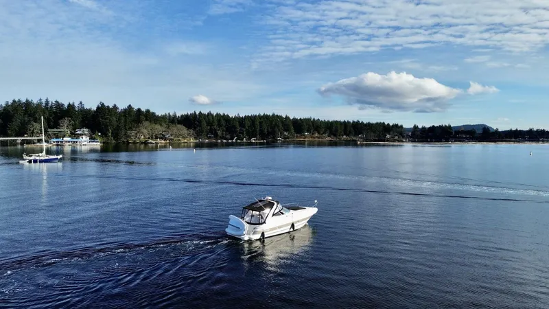  Yacht Photos Pics 2006 Cruisers Yachts 340 Express on serene lake with forested shoreline and cloudy sky.
