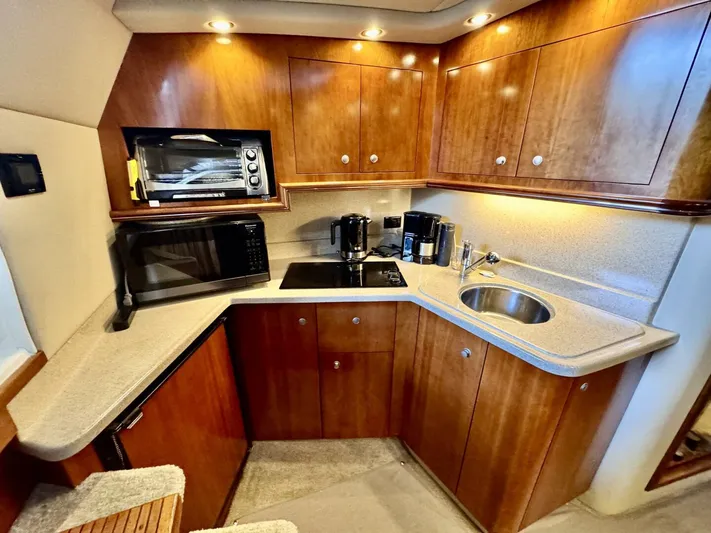  Yacht Photos Pics 2006 Cruisers Yachts 340 Express kitchen with wood cabinets, microwave, stove, and sink.