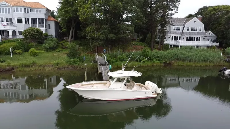  Yacht Photos Pics 2015 Scout 300 LXF boat docked near waterfront homes and lush greenery.
