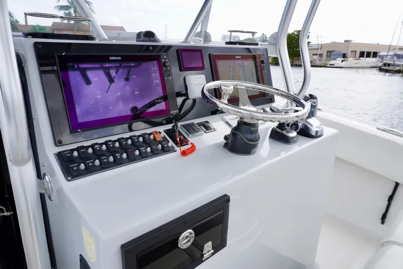  Yacht Photos Pics Control panel of a 2019 Dusky 33 boat with navigation screens and steering wheel.