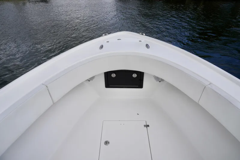  Yacht Photos Pics 2019 Dusky 33 boat bow with white seating and storage, on calm water.