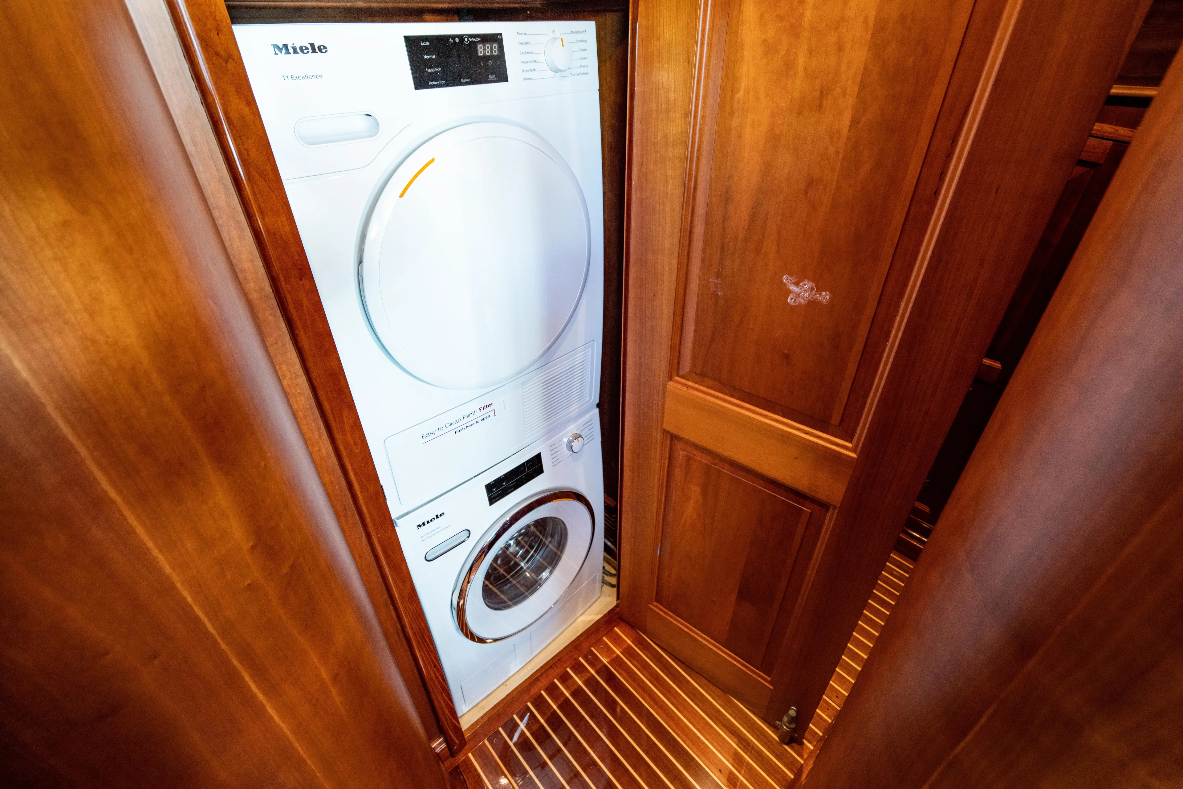 Three Aces Yacht Photos Pics Laundry area with Miele appliances on 2007 Hinckley Talaria 55 FB yacht.