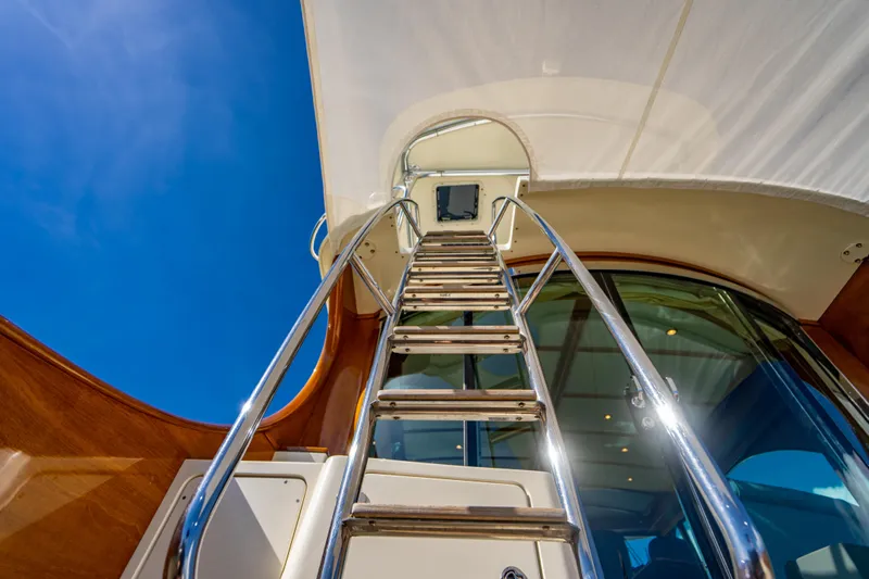 Three Aces Yacht Photos Pics Stainless steel ladder on 2007 Hinckley Talaria 55 FB yacht under clear blue sky.