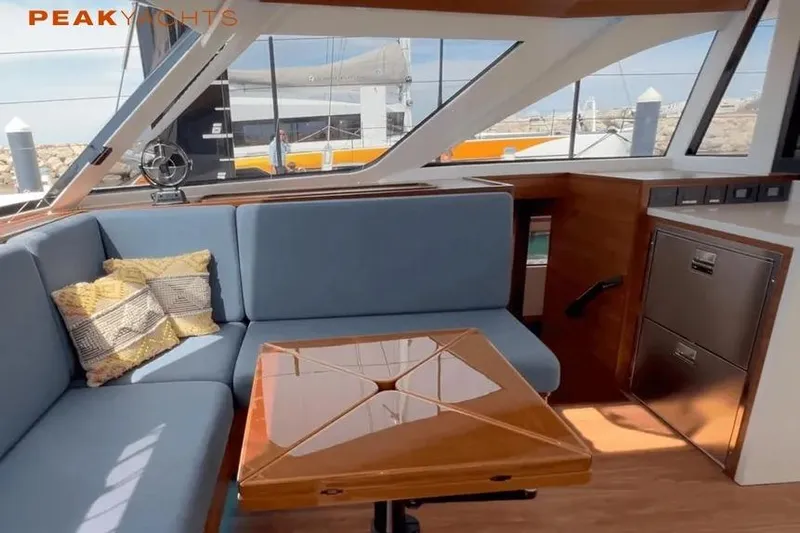 Hoku'au Yacht Photos Pics Luxurious interior of 2025 HH Catamarans HH44 with blue seating and wooden table.