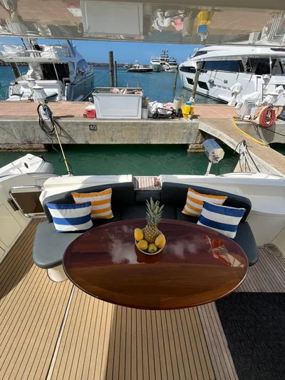  Yacht Photos Pics 2004 Azimut 62 Flybridge yacht with elegant deck seating and fruit centerpiece, docked at marina.