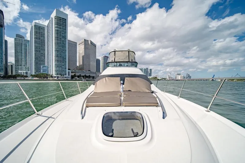  Yacht Photos Pics 2006 Sea Ray 52 Sedan Bridge yacht cruising near city skyline under blue sky.