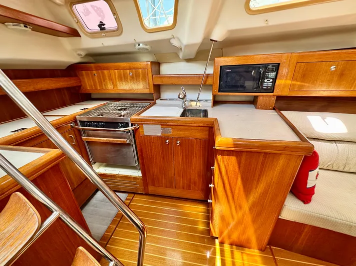Gypsy Palace Yacht Photos Pics 2003 Hunter Passage 420 yacht interior with wooden cabinetry, stove, sink, and microwave.