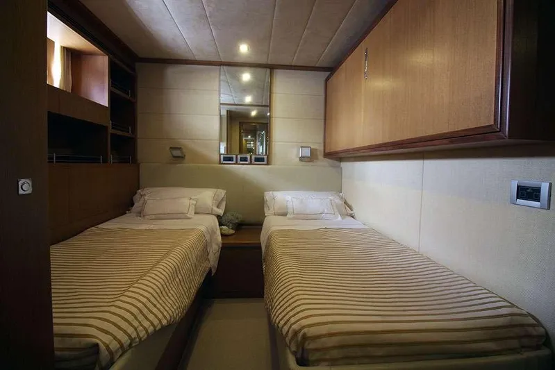  Yacht Photos Pics Twin bedroom in a 2006 Ferretti Yachts 780, featuring striped bedding and wooden cabinetry.