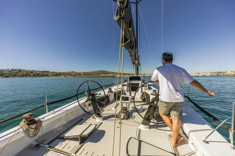 Ground Hog Day Yacht Photos Pics Man steering Rogers 46 sailboat on calm waters, clear blue sky, 2007 model.