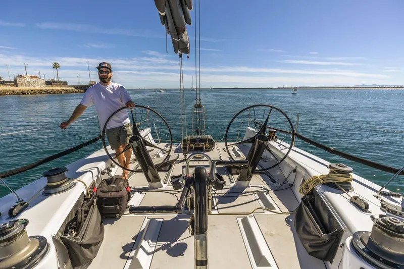 Ground Hog Day Yacht Photos Pics Man steering a 2007 Rogers 46 sailboat on a sunny day at sea.