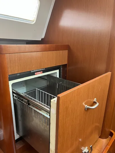 Freedom Yacht Photos Pics Beneteau Oceanis 58 (2011) yacht interior with open wooden cabinet and built-in refrigerator.