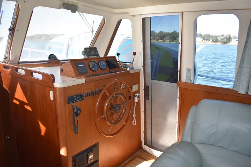  Yacht Photos Pics Interior helm of 2001 Mainship 390 boat with wooden steering wheel and navigation instruments.