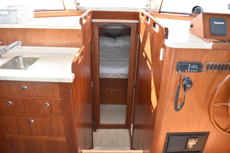  Yacht Photos Pics 2001 Mainship 390 interior with wood cabinetry, sink, and cozy sleeping area.