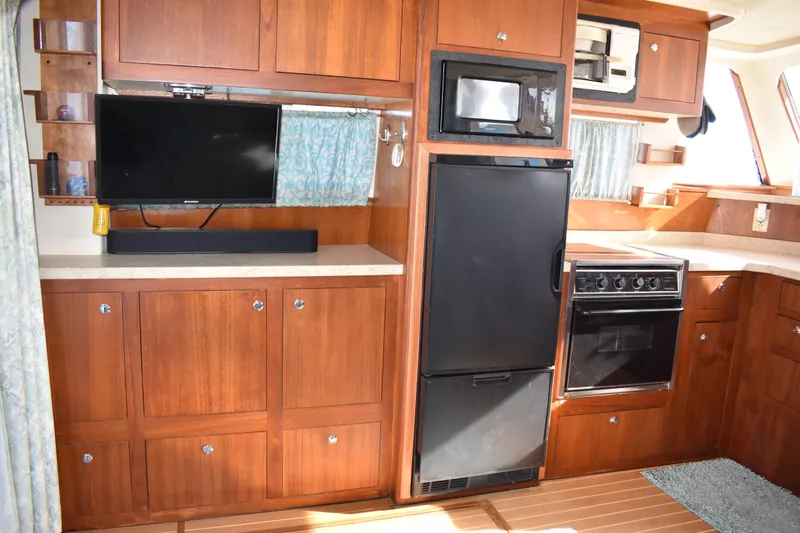  Yacht Photos Pics 2001 Mainship 390 yacht interior with kitchen, featuring wood cabinetry, appliances, and a TV.