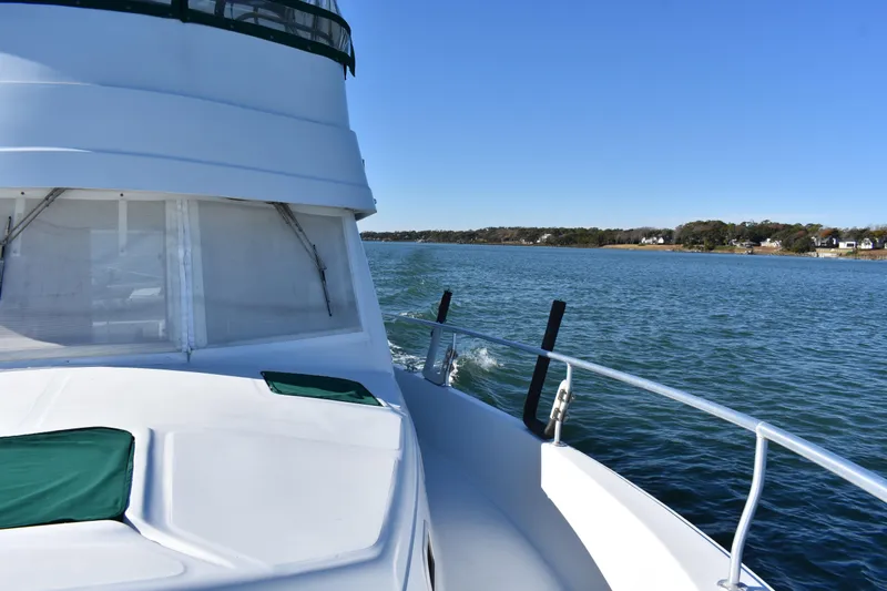  Yacht Photos Pics 2001 Mainship 390 cruising on a serene lake under clear blue skies.