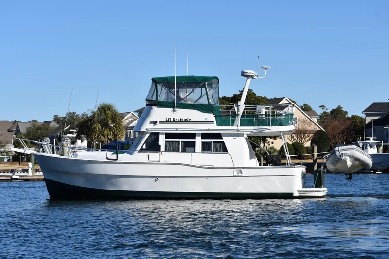  Yacht Photos Pics 2001 Mainship 390 yacht docked in a marina, featuring a green canopy.