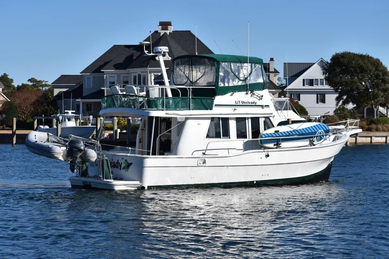  Yacht Photos Pics 2001 Mainship 390 yacht cruising near waterfront homes on a sunny day.