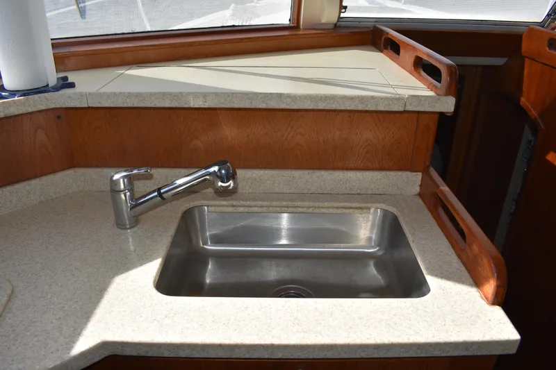  Yacht Photos Pics 2001 Mainship 390 yacht kitchen sink with modern faucet and wooden cabinetry.