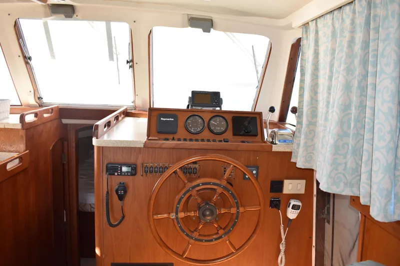  Yacht Photos Pics 2001 Mainship 390 boat interior with wooden helm, navigation instruments, and blue curtains.