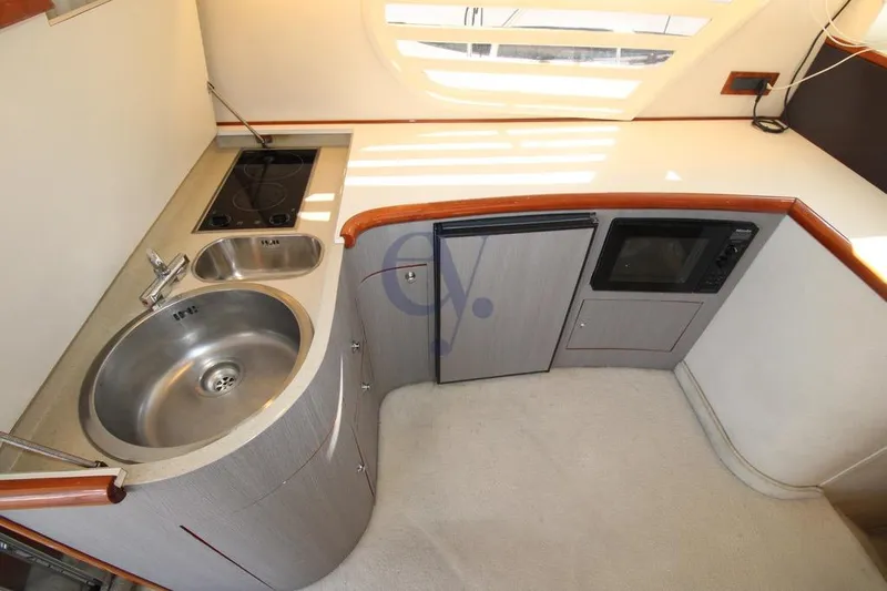  Yacht Photos Pics Compact kitchen area in 2004 Enterprise Marine 43 FLY yacht with sink, stove, and microwave.