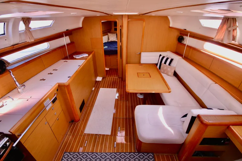 Vela Via Yacht Photos Pics Interior of 2009 Jeanneau 44i sailboat with wooden furnishings and cozy seating area.
