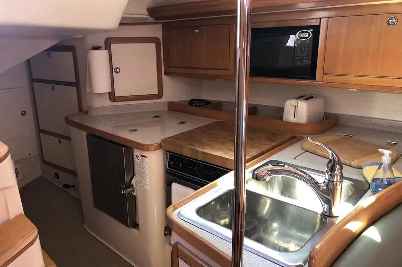 Makani Yacht Photos Pics 2008 Catalina 42 MkII yacht kitchen with sink, stove, and wooden cabinetry.
