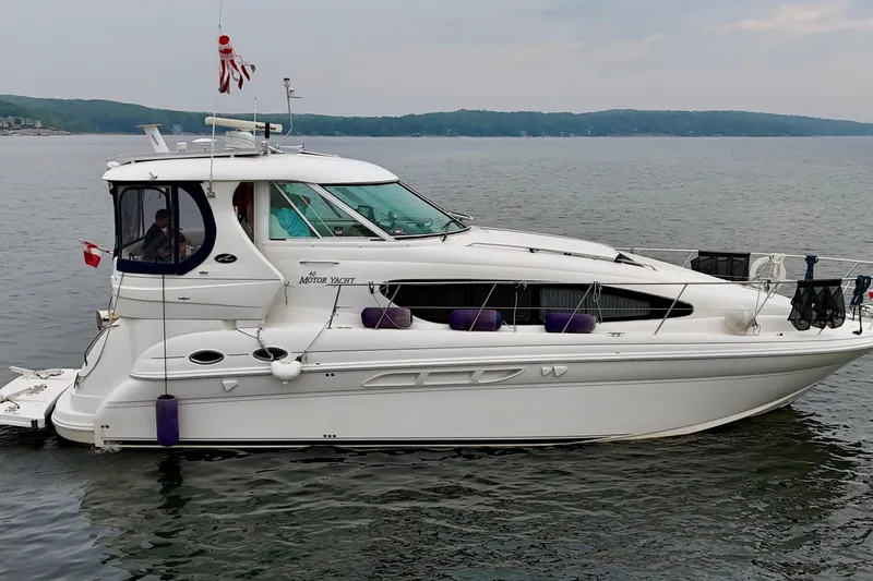 A Mi Manera Yacht Photos Pics 2007 Sea Ray 40 Motor Yacht cruising on a calm lake under a cloudy sky.