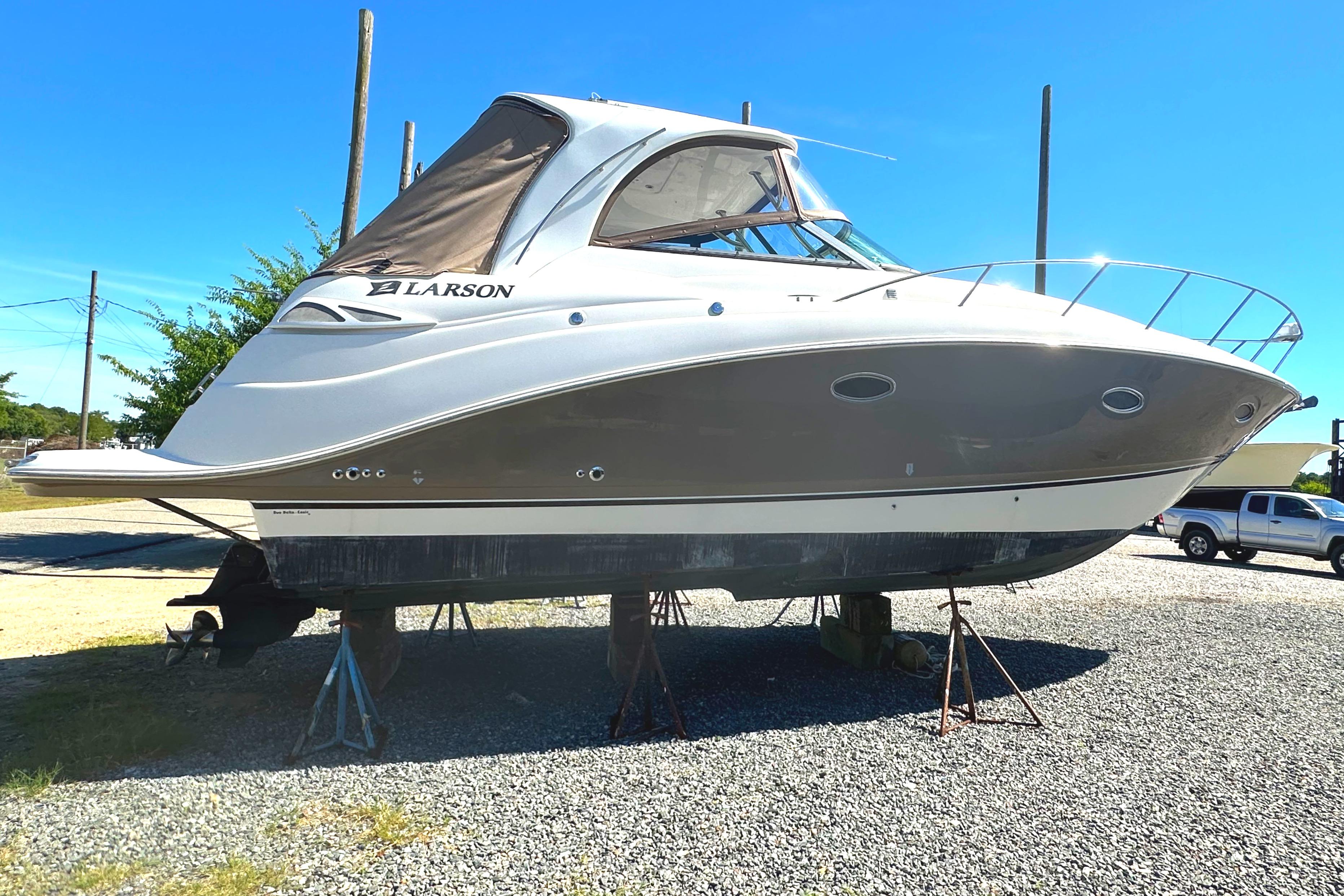 2006 Larson Cabrio 350 boat on stands, displayed outdoors on gravel.