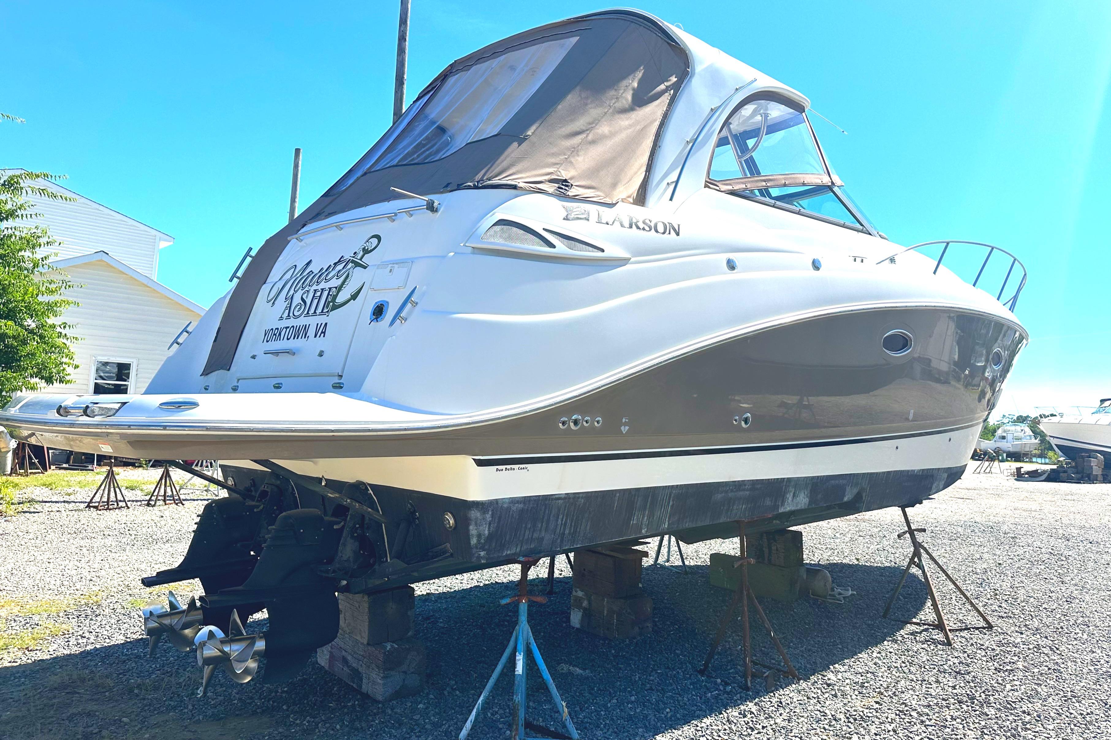 2006 Larson Cabrio 350 boat on stands, outdoor setting, sunny day.